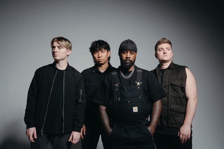 Rock band Sleep Theory standing together in dark casual outfits posing against a plain gray studio backdrop.